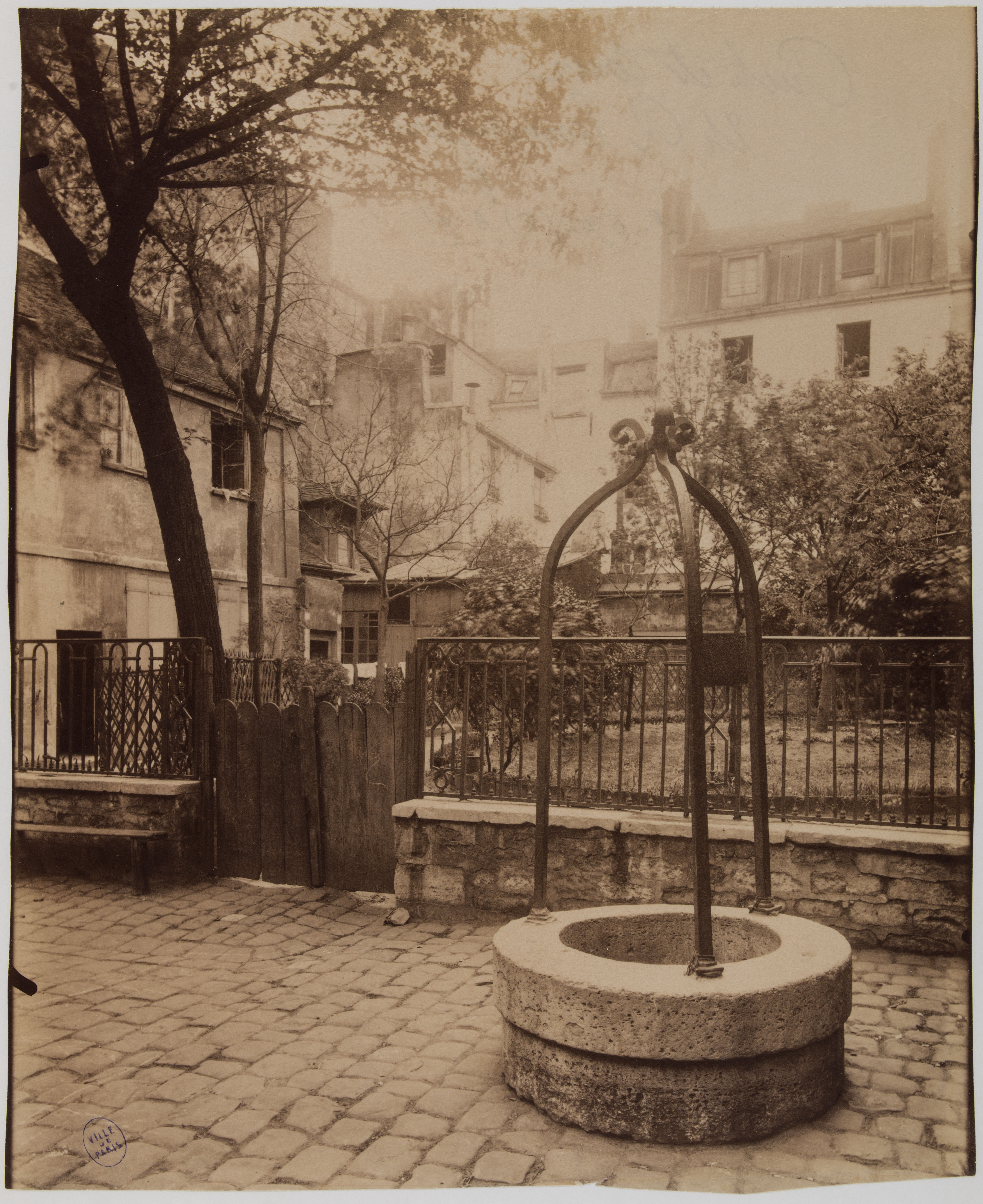 Photographie ancienne d'une cour pavée et d'un puits au 24 rue Tournefort par Eugène Atget